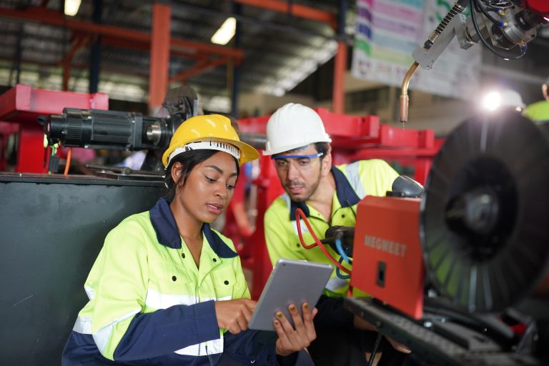 Robotics engineer working on maintenance of modern robotic arm in factory warehouse. Business technoloy