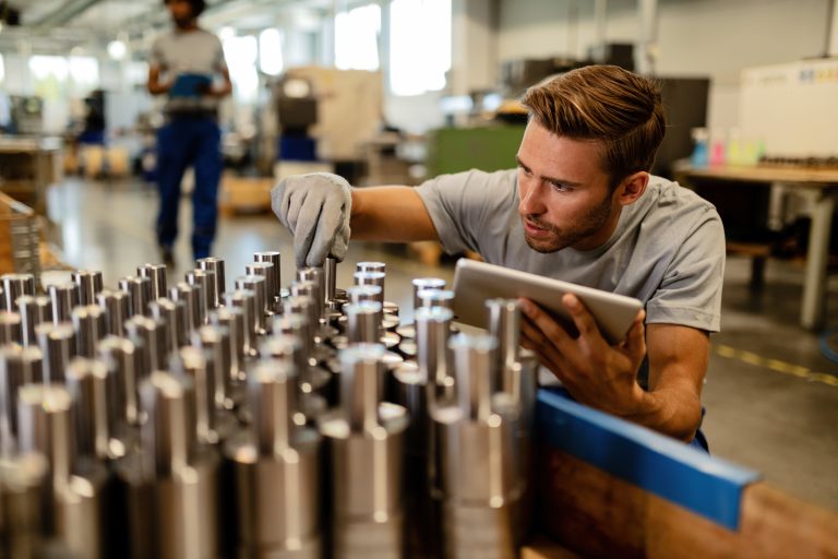 Young steel worker performing quality control of manufactured products in a warehouse